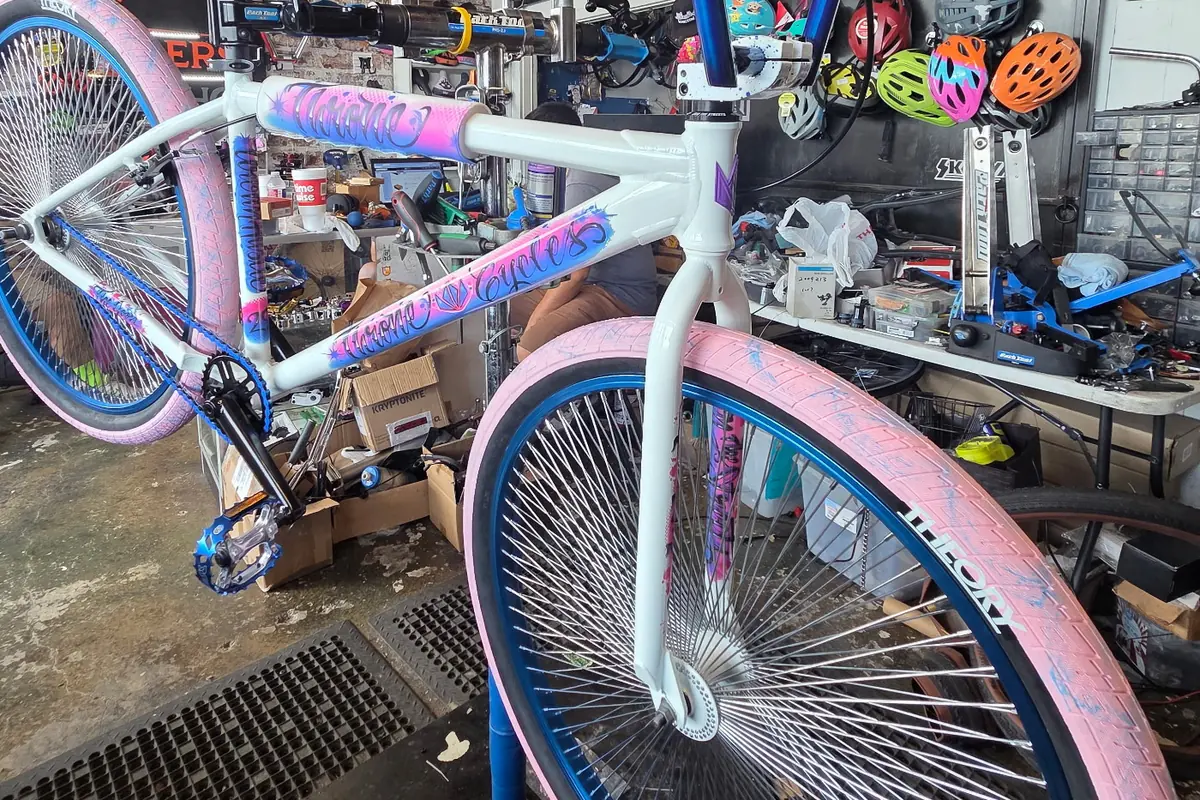 White frame with pink and blue graffiti graphics and blue rims