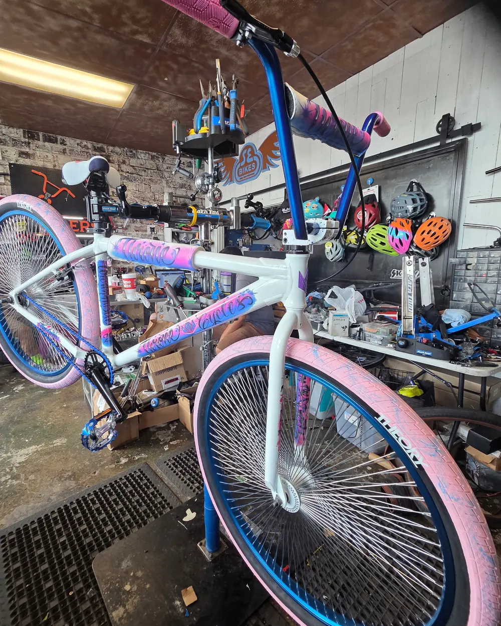 White frame with pink and blue graffiti graphics, pink tires and blue rims
